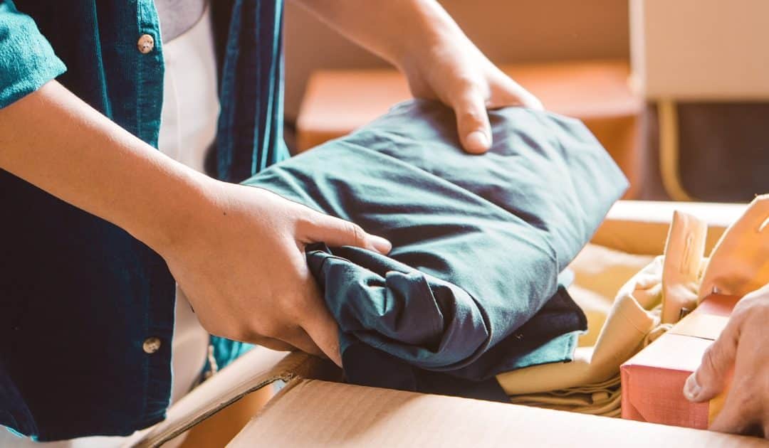 Hands folding clothing to place in a moving box