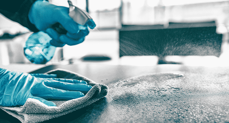 person with blue gloves cleaning surface