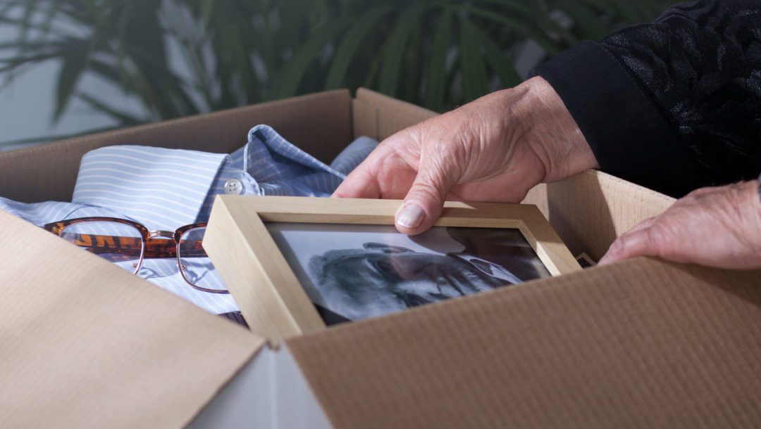 Woman packing dead husband's photography to moving box