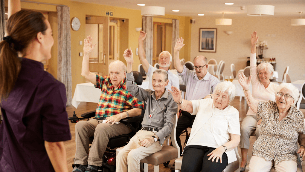 Seniors living in one of the types of senior living options raising their hands